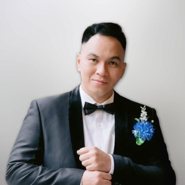 Gambar Billy Sondakh, anggota Biro Media Cetak & Elektronik serta Biro Multimedia di bawah Majelis Daerah GPdI Australia. Billy tampil mengenakan jas hitam dengan lapisan satin di bagian kerah, dipadukan dengan kemeja putih dan dasi kupu-kupu berwarna hitam. Di bagian dada kiri terdapat aksesoris bunga berwarna biru terang dengan hiasan hijau dan putih, memberikan nuansa elegan dalam acara formal. Background gambar berwarna abu-abu terang polos, memperjelas fokus visual pada subjek utama. Foto ini merupakan bagian dari dokumentasi resmi kepengurusan GPdI Australia dalam sektor media dan komunikasi digital.